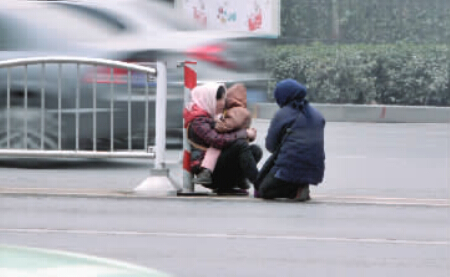 郑州街头女子抱孩子车流中乞讨 劝离遭拒绝